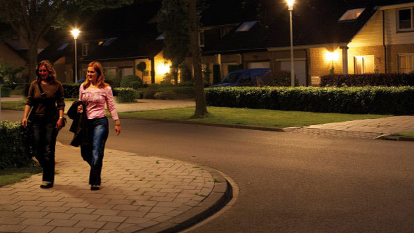 To kvinner går i en gate som er belyst med hvitt lys fra Philips