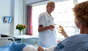 En sykepleier gir et glass vann til en pasient