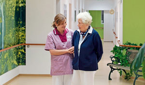 En sykepleier som hjelper en eldre dame i en belyst gang