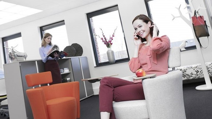 En kvinne prater i telefonen under Soundlight Comfort-systemet Ideell kontorbelysning gir mer behagelige arbeidsplasser.