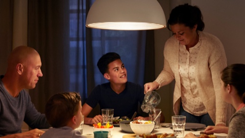 Familie spiser middag hjemme ved et godt belyst spisebord