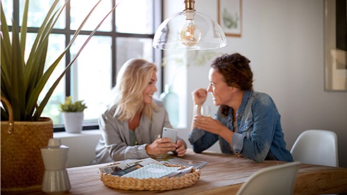 To kvinner har en samtale hjemme under en Philips lyspære