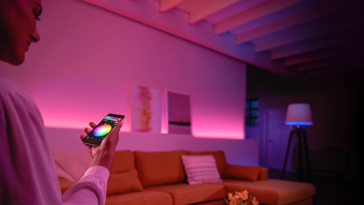 Person kontrollerer fargerikt lys i en stue