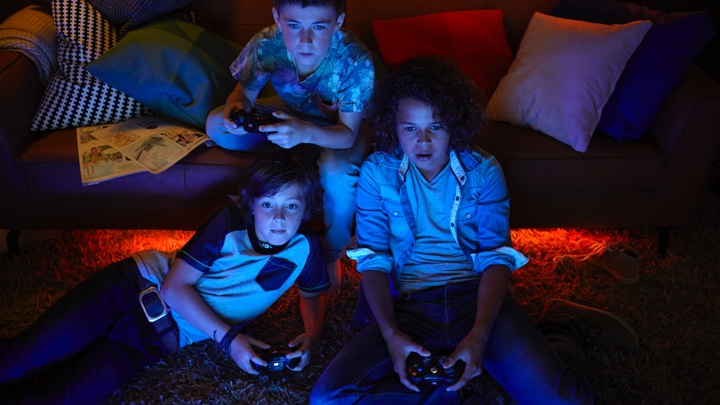 Tre gutter spiller videospill med stemningslys