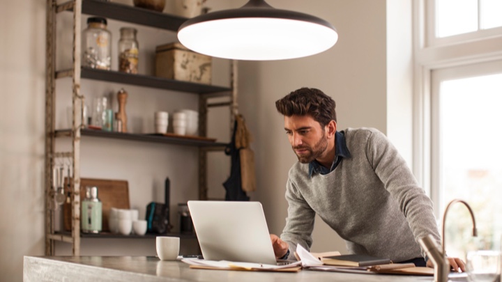 En mann jobber hjemme under en intelligent lampe