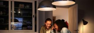 "Moderne LED-pendellys skaper en varm atmosfære for to kvinner som nyter samtalen, og viser frem energieffektive hjemmebelysningsløsninger."